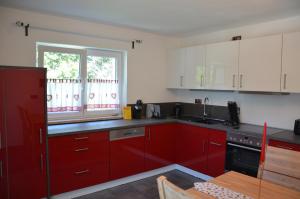 a kitchen with red cabinets and a window at Ferienwohnungen am Schambacher Weg in Riedenburg