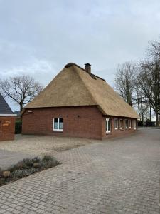 een groot bakstenen gebouw met een rieten dak bij Ferienwohnung Schipmann in Krempdorf