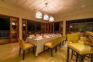 a dining room with a long table and yellow chairs at Villa Salazie in Mahe