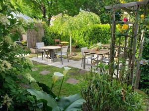ogród ze stołami i krzesłami oraz pergolą w obiekcie Chambres d'hôtes couleur bassin d'Arcachon w mieście Andernos-les-Bains