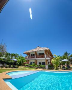 a villa with a swimming pool in front of a house at Scent of Green Papaya in Panglao Island