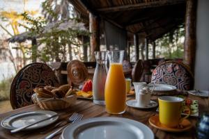 a wooden table with a glass of orange juice at Kisima Ngeda Camp in Mangola +14 photos