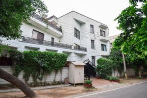 a white building with a fence next to a street at BedChambers Serviced Apartments, Sushant Lok in Gurgaon