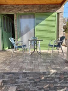 een tafel en stoelen op een patio met een groene deur bij Cosmitsa House in Vingláfia