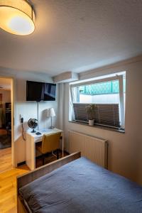 a bedroom with a bed and a desk and a window at Gemütliche 2-Zimmer Souterrain Wohnung in Düsseldorf