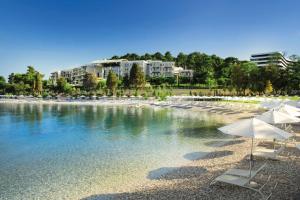 una playa con sillas y sombrillas en el agua en Vila Una with private pool near Rovinj - open 2022, en Rovinjsko Selo