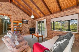 a brick walled living room with couches and a tv at Coucals Cottage in Mount Crosby