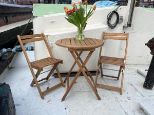 een tafel en twee stoelen en een vaas met bloemen bij Skinny Bridge Houseboat Amstel View Amsterdam in Amsterdam