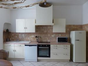 a kitchen with white cabinets and a white refrigerator at L'Incarnat in Caunes-Minervois