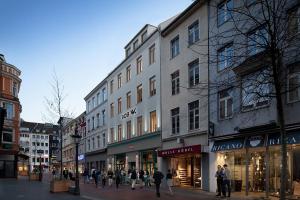 a group of people walking down a city street with stores at Bob W Beethoven in Bonn