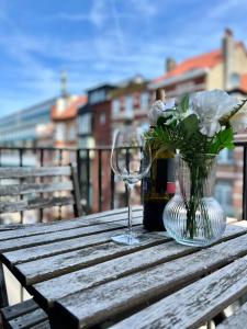 un vaso di fiori e un bicchiere di vino su un tavolo di legno di Lovely 2-bedroom Duplex w/ balcony in Brussels a Bruxelles