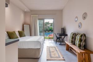 a bedroom with a bed and a bench and a patio at Saronis Suites in Saronida