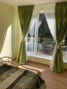 a bedroom with a bed and a window with curtains at Laimdotas in Jūrmala