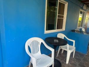 Dos sillas blancas y una mesa y una pared azul. en PhiPhi Film House, en Islas Phi Phi
