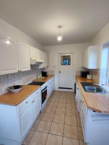 una cocina con armarios blancos y encimeras de madera en Beachgrove House, en Bristol