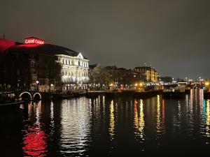 een stad 's nachts met lichten op het water bij Skinny Bridge Houseboat Amstel View Amsterdam in Amsterdam