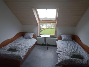 Duas camas num pequeno quarto com uma janela em Agroturystyka Żuczek em Okuniowiec