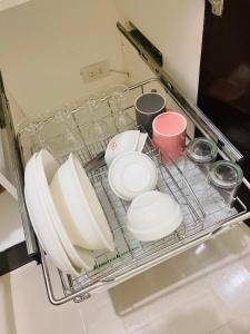 a dish rack with plates and cups in a refrigerator at Cozy Condo with Surround Sound for Netflix in Manila