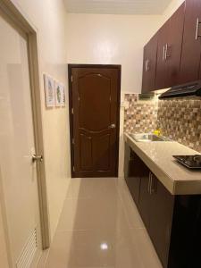 a kitchen with a brown door and a sink at Cozy Condo with Surround Sound for Netflix in Manila