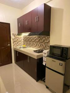 a kitchen with a microwave and a sink and a stove at Cozy Condo with Surround Sound for Netflix in Manila