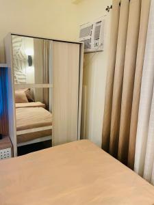 a mirror in a room with a bed and a bedroom at Cozy Condo with Surround Sound for Netflix in Manila