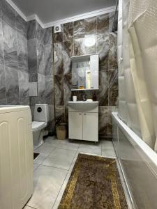 een badkamer met een wastafel, een toilet en een spiegel bij 2х комнатная квартира в ЖК Тавангар с евроремонтом in Aqtöbe