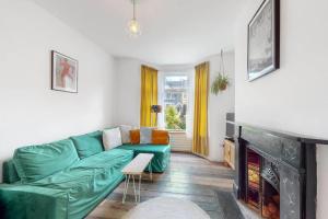 un soggiorno con divano verde e camino di Enchanting 3 bedroom house with garden in Leyton a Londra