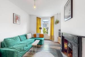 a living room with a green couch and a fireplace at Enchanting 3 bedroom house with garden in Leyton in London