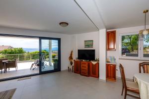 een woonkamer met televisie en een balkon bij Apartment "Villa M" in Kostrena