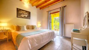a bedroom with a bed and a desk and a window at Zen Stone House in Agios Georgios Pagon