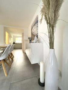 Moderne, hochwertig ausgestattete Hausscheibe in Sackgassenlage! في Westerholz: غرفة معيشة مع مزهرية بيضاء مع الزهور فيها
