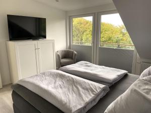1 Schlafzimmer mit 2 Betten, einem TV und einem Stuhl in der Unterkunft Moderne, hochwertig ausgestattete Hausscheibe in Sackgassenlage! in Westerholz