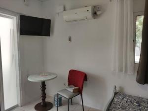 een kamer met een stoel, een tafel en een tv bij Όμορφο διαμέρισμα με μπαλκόνι στη Σαρωνίδα in Saronida