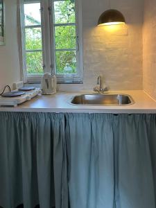 a kitchen counter with a sink and a window at Anne Just's Havehotel in Blokhus