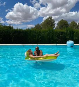 a man and a woman on a raft in a swimming pool at Casa Rural Finca Juanamare in Yecla