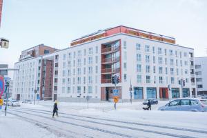 uma pessoa a atravessar uma rua em frente a um edifício branco em Snowflake Suites VI em Rovaniemi