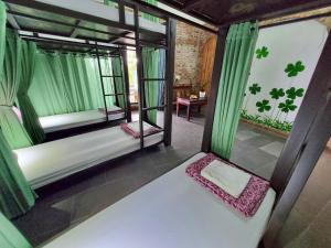 um quarto com uma cama e janelas com cortinas verdes em Calm House 2 HOSTEL em Hoi An