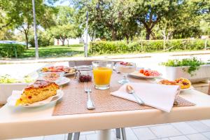 einen Tisch mit Essen und Orangensaft darauf in der Unterkunft Hotel Agugliastra in Santa Maria Navarrese