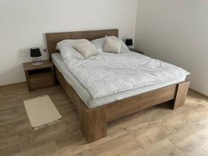 a bedroom with a wooden bed with white sheets and pillows at Apartamenty Aleksandra in Biały Dunajec