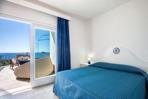 a bedroom with a blue bed and a balcony at Hotel Agugliastra in Santa Maria Navarrese