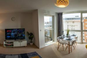 een woonkamer met een televisie en een tafel en stoelen bij Rueben Suite By Koya Homes - Cardiff in Cardiff