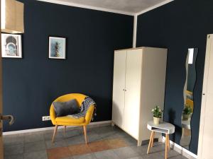 una silla amarilla en una habitación con una pared azul en Ferienwohnung am Nurburgring, en Welcherath