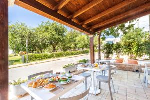 une terrasse avec des tables et des chaises et de la nourriture. dans l'établissement Hotel Agugliastra, à Santa Maria Navarrese