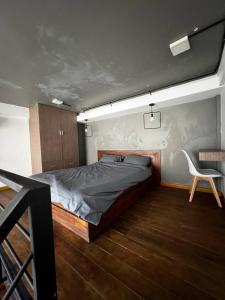 a bedroom with a bed and a white chair at liora Cambodia - Riverside Loft Apartments in Phnom Penh