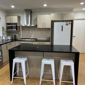 a kitchen with a black counter and two white stools at Beautiful 2 Bedroom Home in Auckland