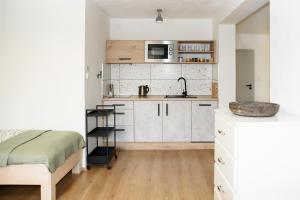 uma cozinha com armários brancos e uma cama num quarto em Apartmán Mločí údolí • Podyjí em Znojmo