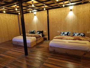 2 camas en una habitación con paredes de madera en Awana Cottages, en Harsil