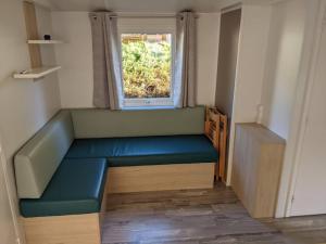 Camping 4 étoiles DOMAINE D'EUROLAC في Aureilhan: غرفة صغيرة مع أريكة زرقاء ونافذة