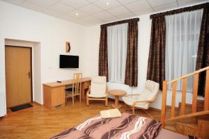 Cette chambre comprend un bureau, une table et des chaises. dans l'établissement Penzion Budopartner, à Jívka