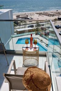 een tafel met twee flessen en een hoed op een balkon bij Sea la Vie Apt 240 in Infinity Beach Resort - parking in Mamaia